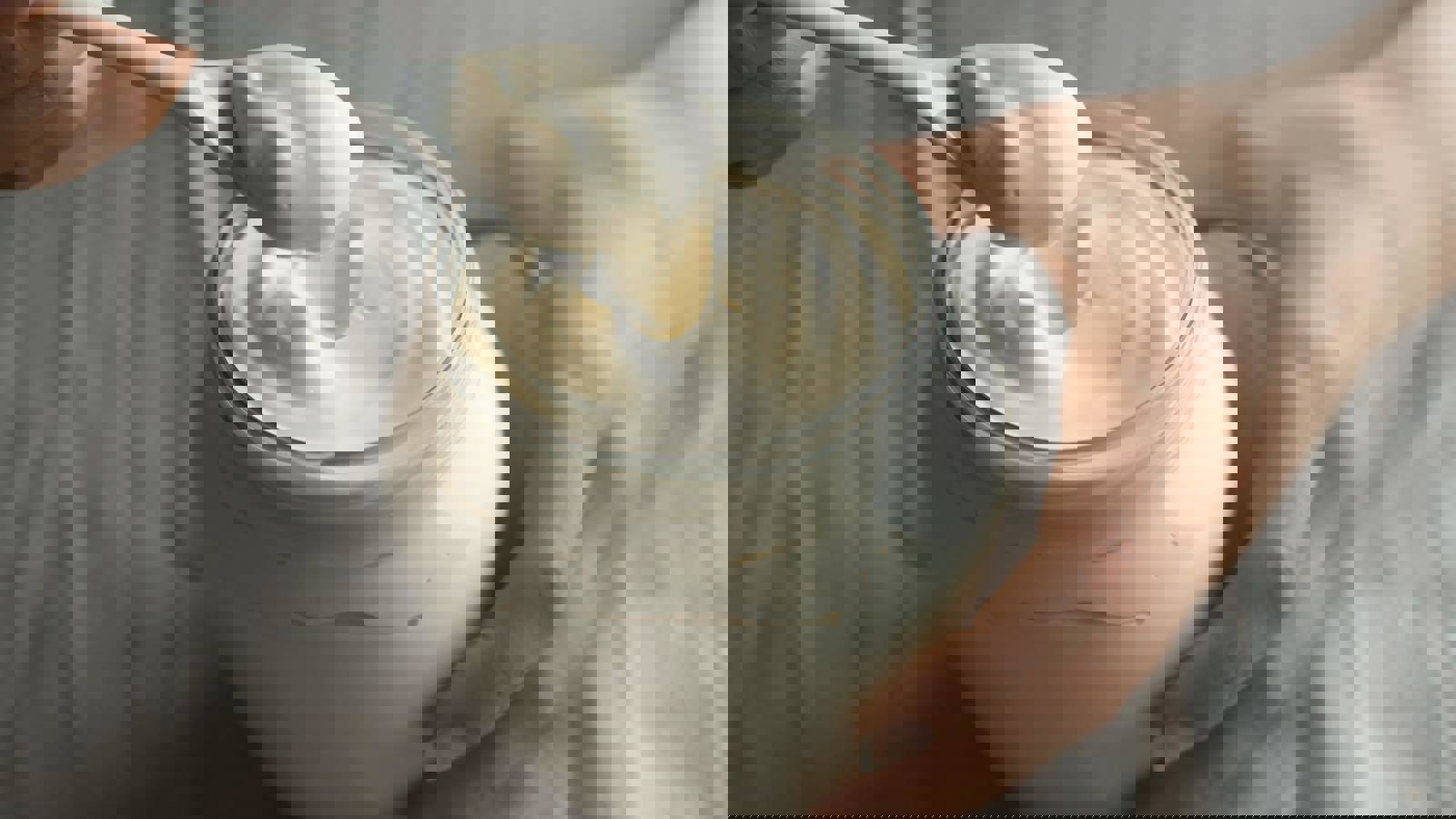 Female hands with spoon taking mayonnaise from a jar