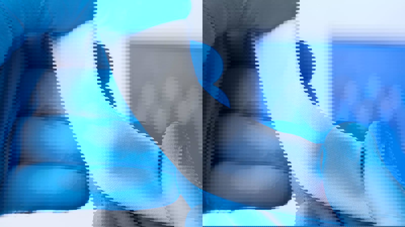 Hands wearing blue gloves hold biocompatible material