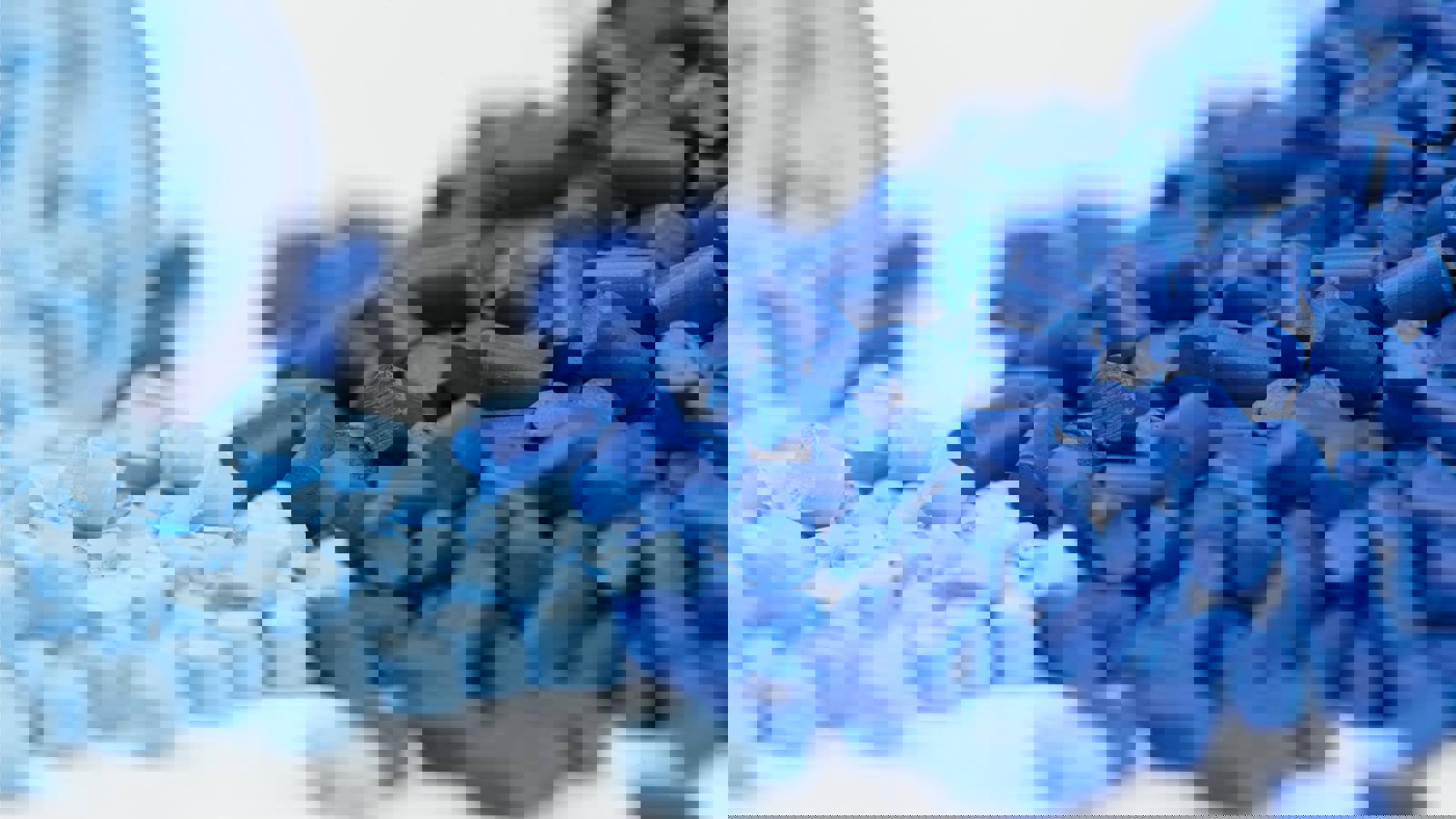 Dark and light blue polymer granules on white background