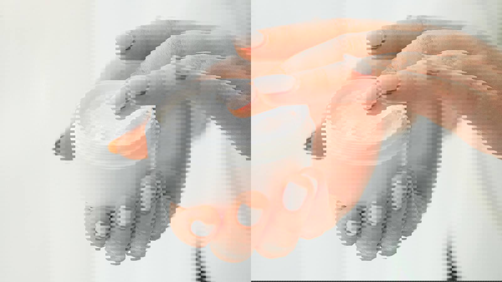 Hands holding a pot of cosmetic cream
